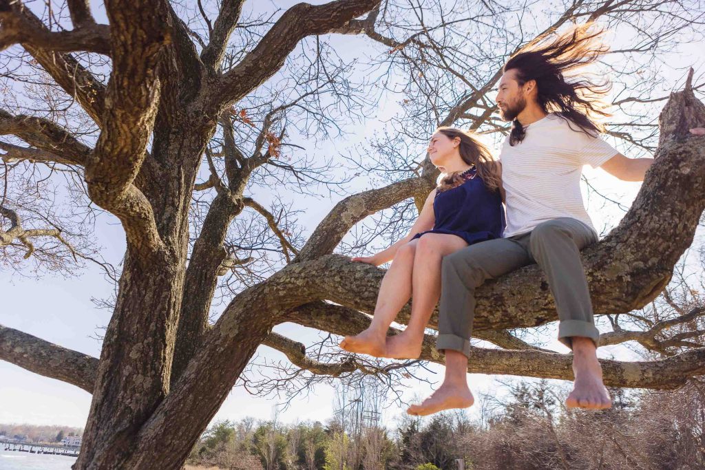 A man and woman sitting on a tree branch, captured in a family portrait.