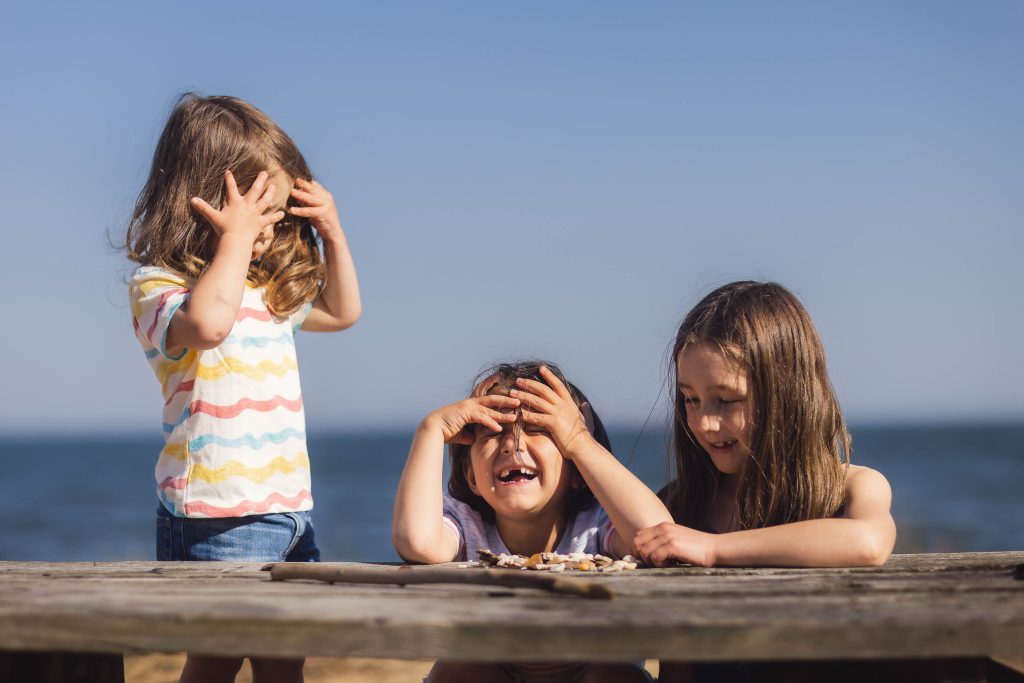 Three little girls sitting at a picnic table in Annapolis, Maryland, with their hands covering their eyes.