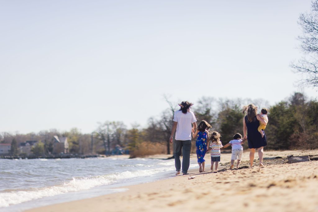 A Maryland family walking on the beach near a body of water.