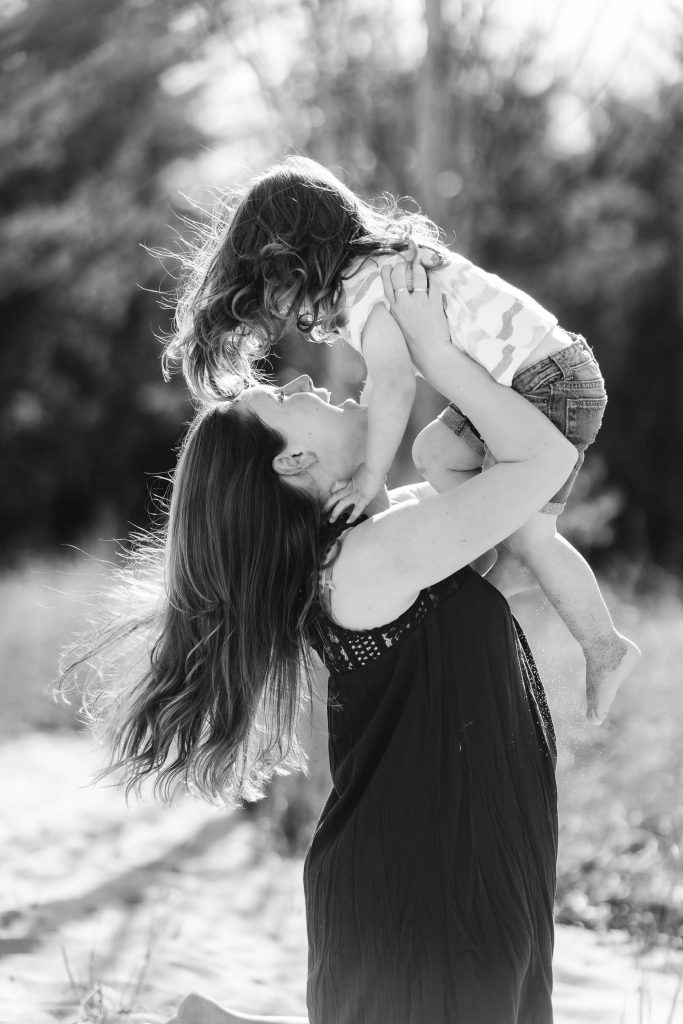 A portrait of a woman holding her daughter in the air, taken in Annapolis near the Chesapeake Bay Foundation.