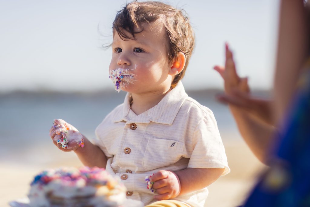 A young boy eating a birthday cake on the beach in Annapolis, Maryland.