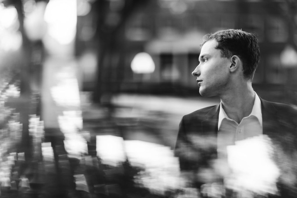 A high school senior poses for his graduation portrait in downtown Annapolis wearing a black and white suit.