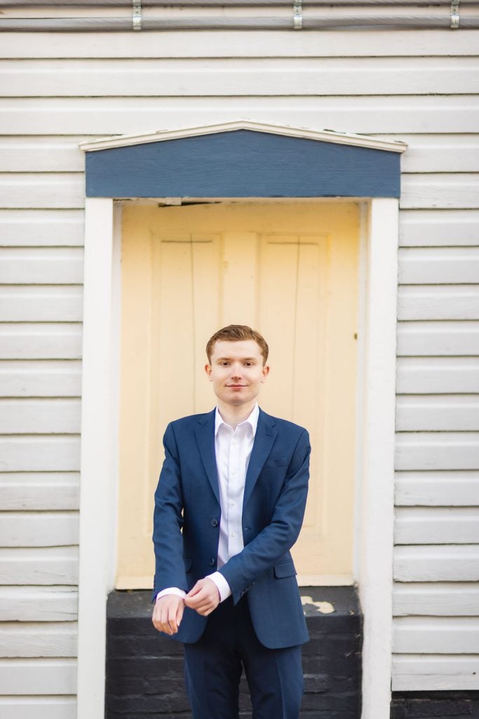 A High School Senior in a suit standing in front of Downtown Annapolis building for his Graduation Portrait.