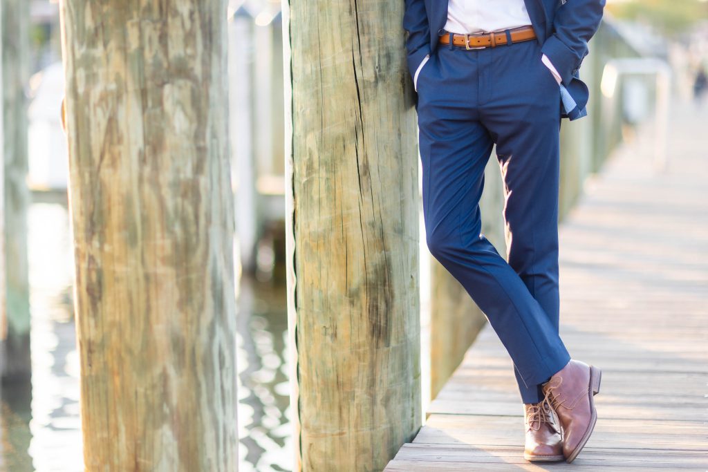 A High School Senior in a blue suit leaning against a wooden post in Downtown Annapolis.