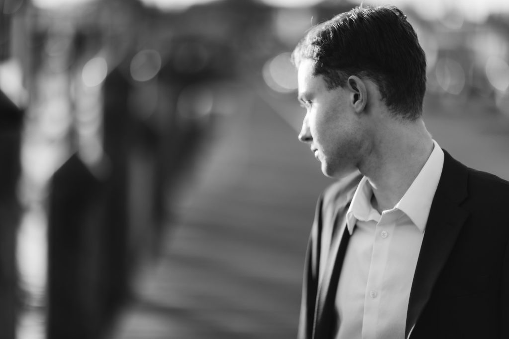 A black and white photo of a High School Senior in a suit on graduation day.