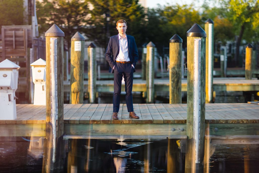 A High School Senior in a suit standing on a dock in Downtown Annapolis, capturing the essence of a Graduation Portrait.