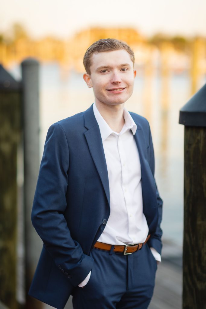 A High School Senior in a blue suit standing on a dock in Downtown Annapolis for his Graduation Portrait.