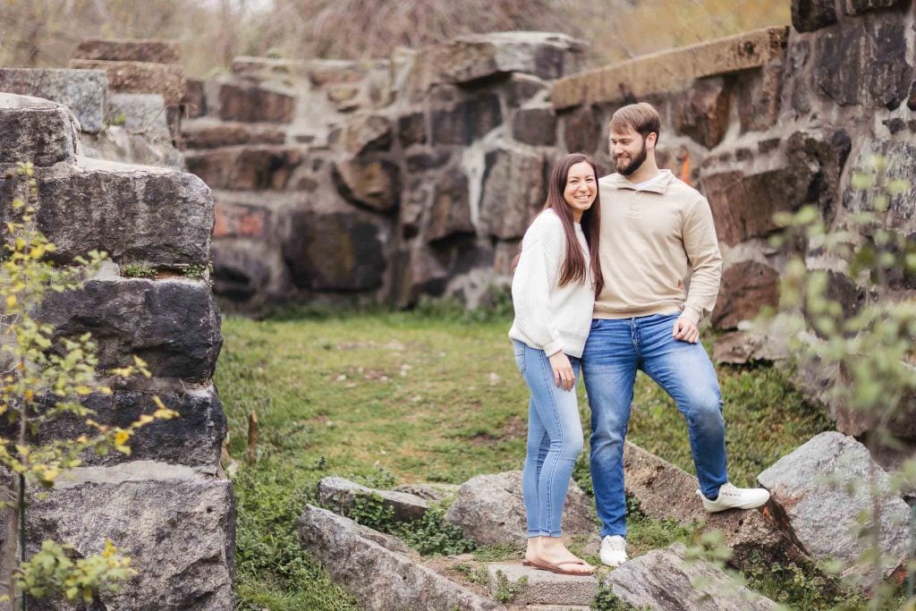 An engaged couple posing for a portrait on a stone path in Old Ellicott City's park.