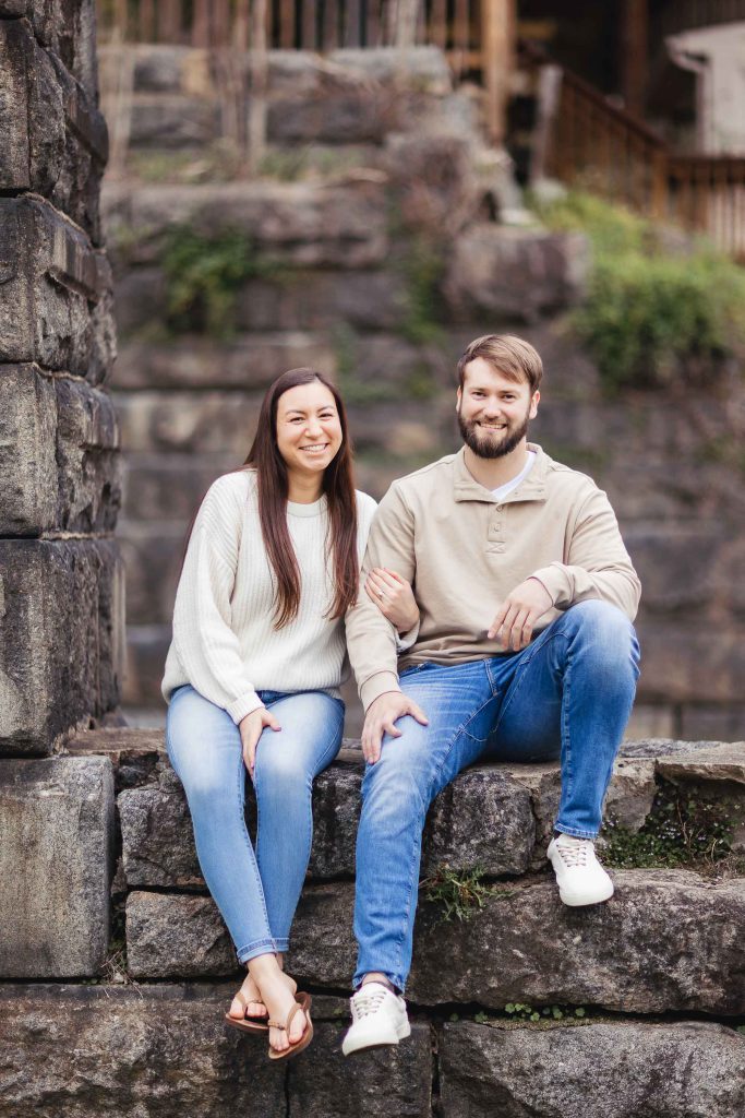 A couple poses for their engagement photo on a stone wall in Old Ellicott City.