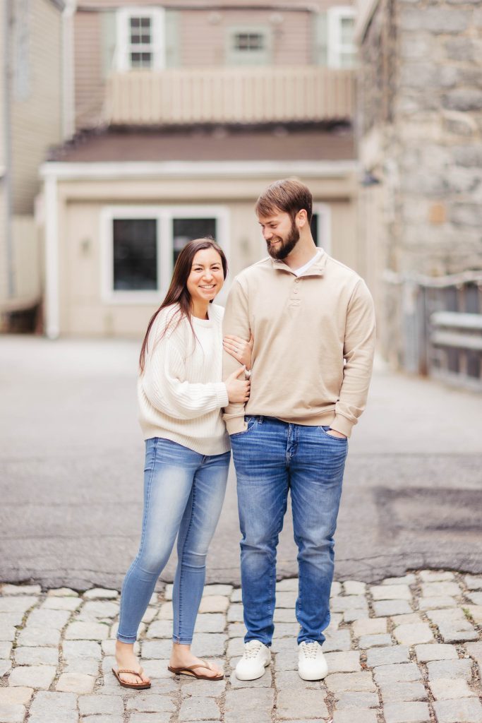 A portrait of an engaged couple standing on a cobblestone street in Old Ellicott City.