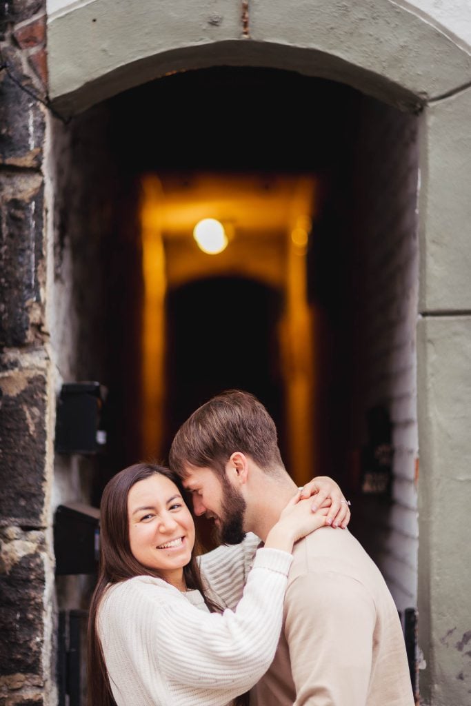 An engagement photo captures a couple in front of an archway in Old Ellicott City during their portrait session.