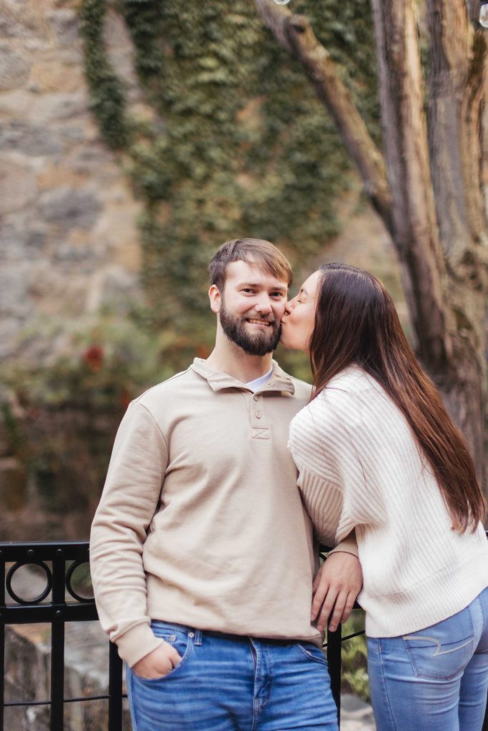 An engagement photo of a couple passionately kissing in front of an old stone wall in Old Ellicott City.