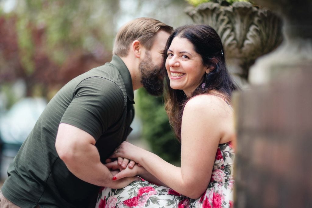An engaged couple posing for their engagement photos, leaning against a wall in downtown Annapolis.