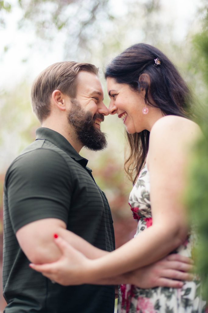 A couple smiles as they look at each other during their engagement portrait session in downtown Annapolis.
