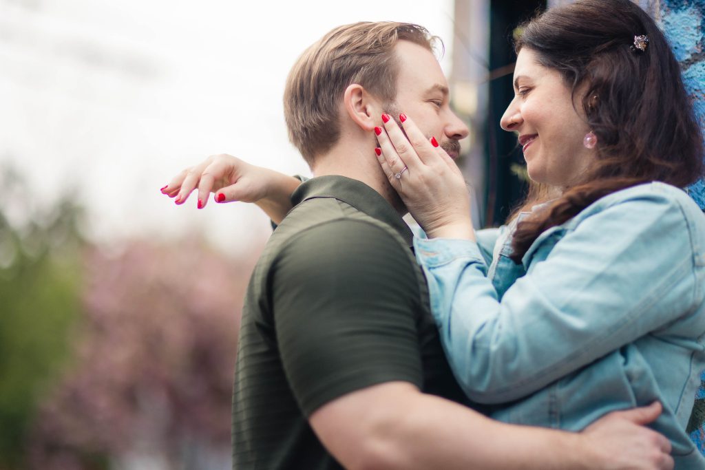 A portrait of a man and woman hugging in front of a wall in downtown Annapolis.