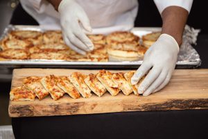 Spilled Milk Catering cutting bread on a cutting board as an event vendor.