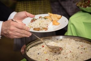 A Spilled Milk Catering vendor is holding a plate of rice.