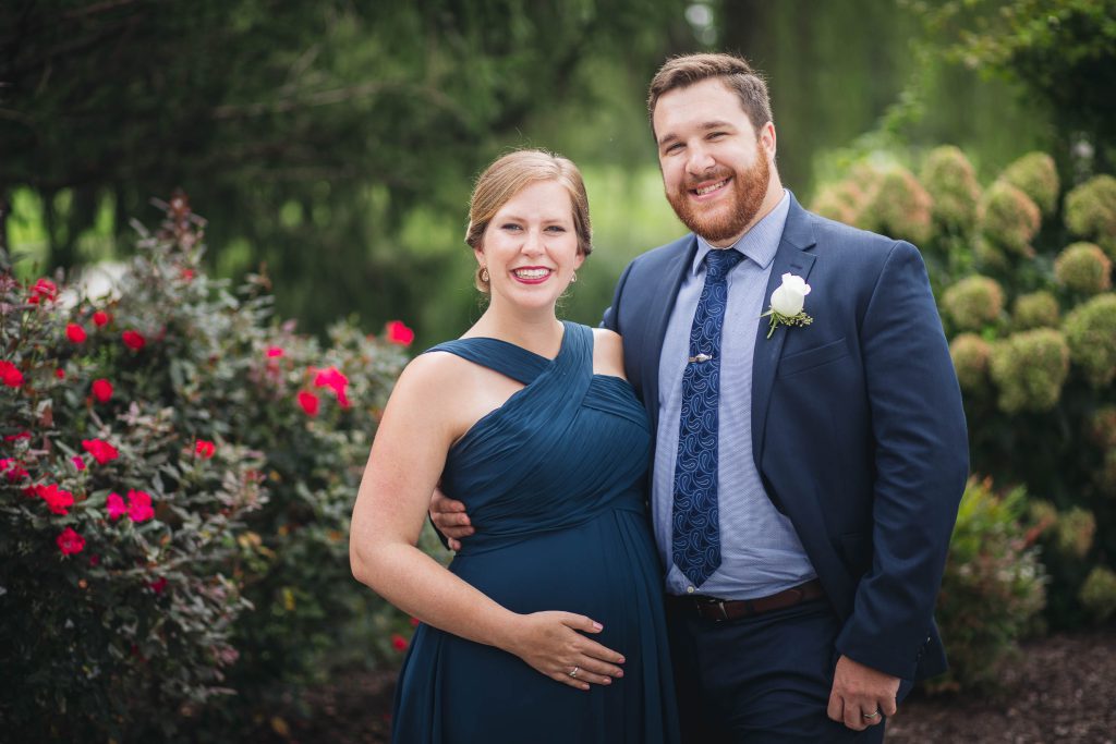 A couple posing for a photo in front of bushes at Turf Valley Resort in Ellicott City, Maryland.