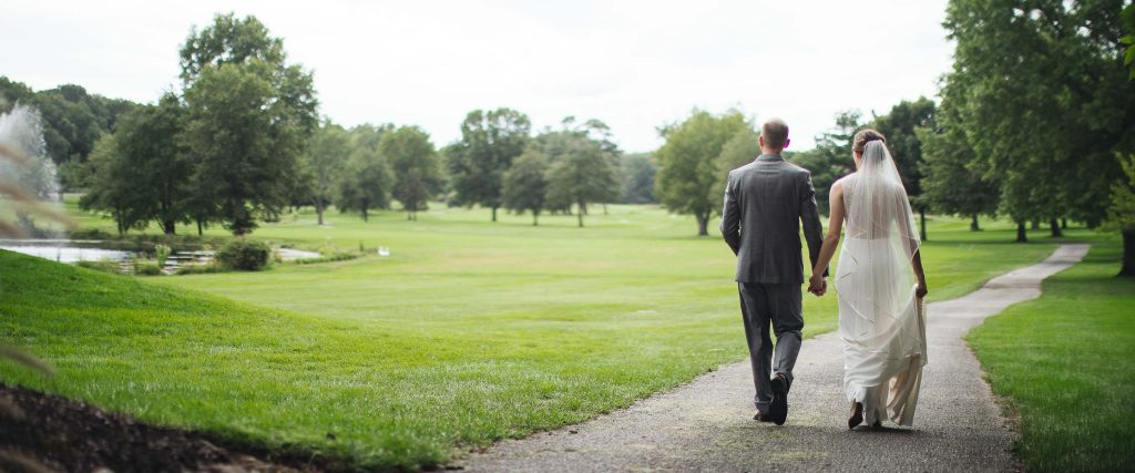 A bride and groom walking down a path at Turf Valley Resort.