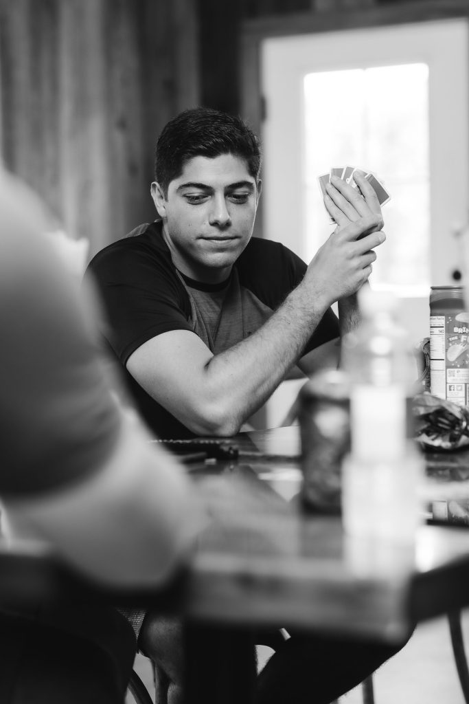 A candid man sitting at a table with a card in his hand at Fleetwood Farm Winery.