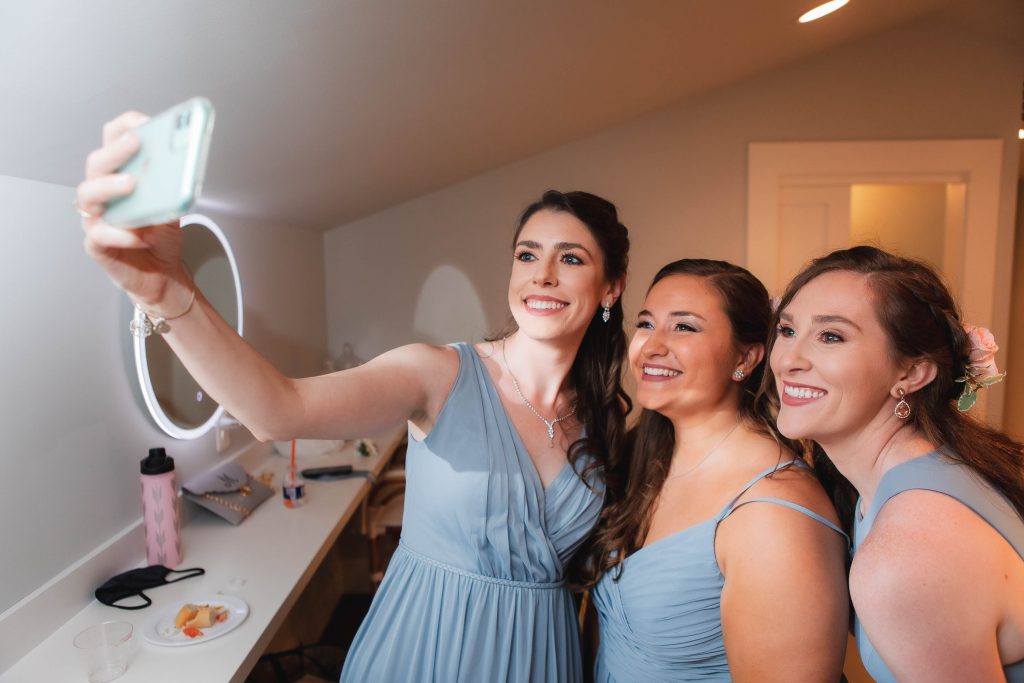 Candid bridesmaids taking a selfie at a wedding.