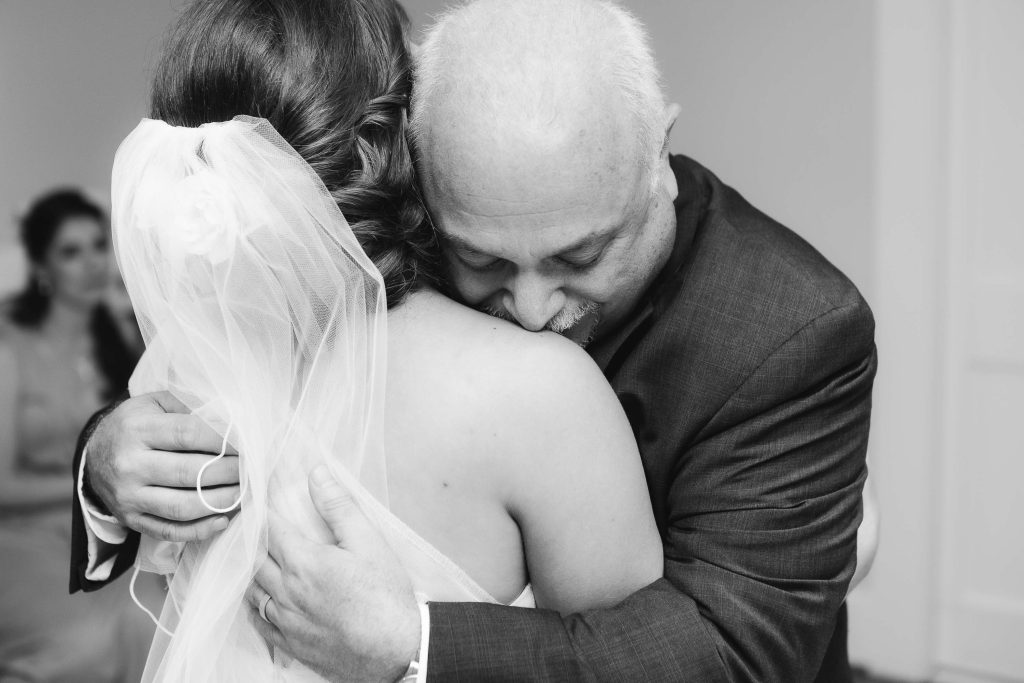 A candid black and white photo of a bride hugging her father on her wedding day at Fleetwood Farm Winery.