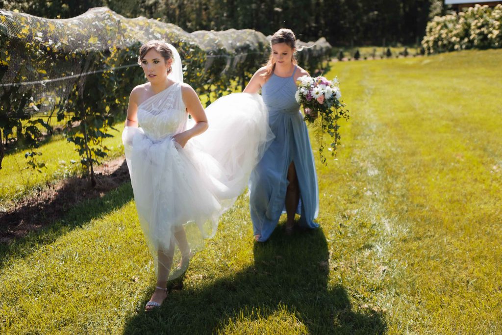 Two bridesmaids candidly walking through a vineyard during a wedding at Fleetwood Farm Winery.