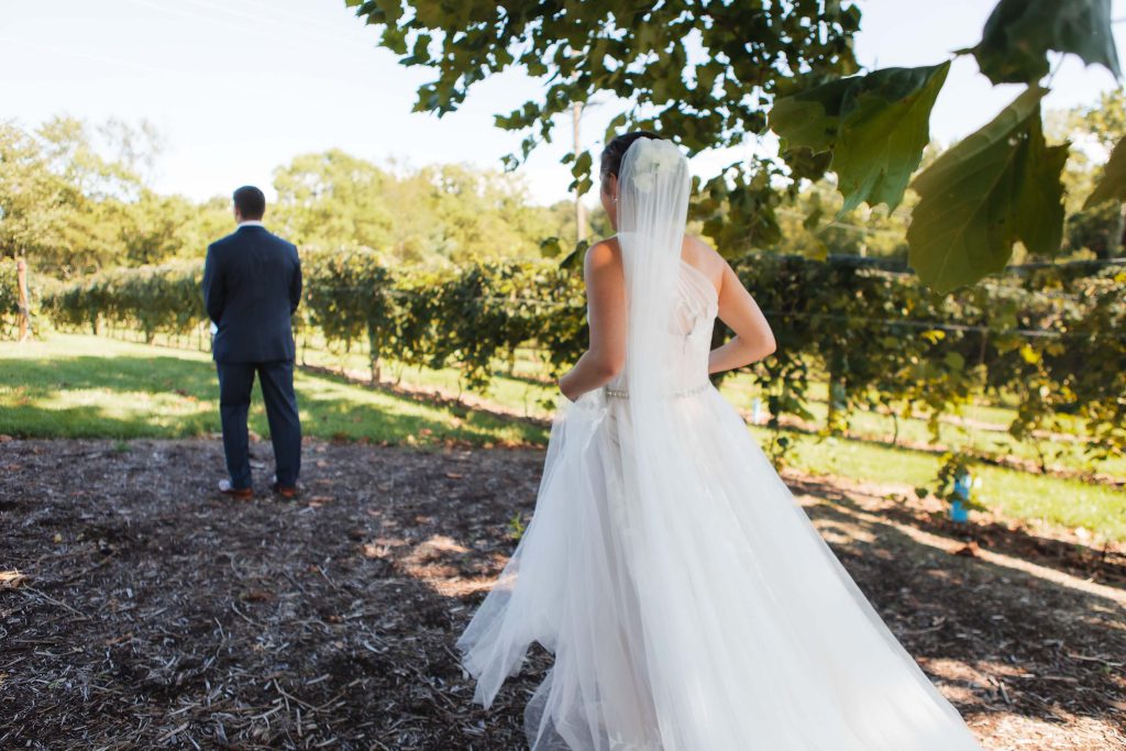A candid wedding couple standing in the beautiful vineyard of Fleetwood Farm Winery.