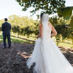 A candid wedding couple standing in the beautiful vineyard of Fleetwood Farm Winery.