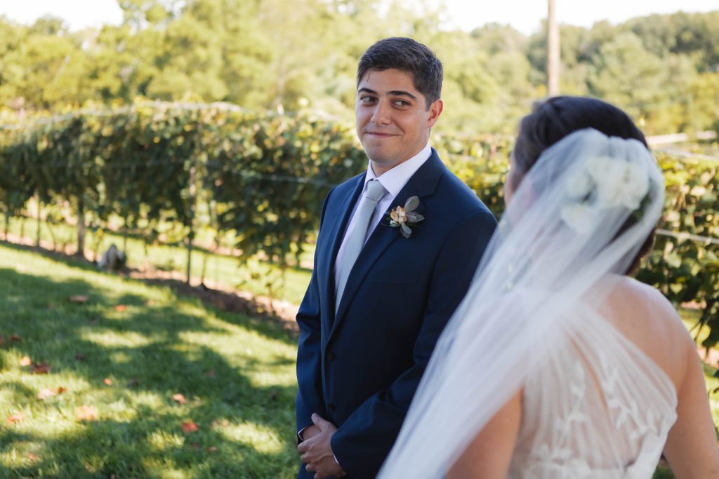A candid wedding moment captured at Fleetwood Farm Winery, as the bride and groom lock eyes in a beautiful vineyard setting.