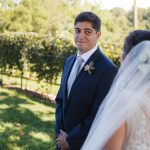 A candid wedding moment captured at Fleetwood Farm Winery, as the bride and groom lock eyes in a beautiful vineyard setting.