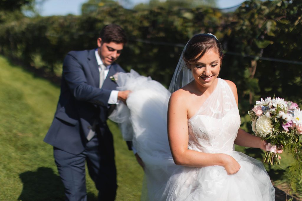 A Wedding couple walking through Fleetwood Farm Winery, captured in a candid moment amidst the vineyard.