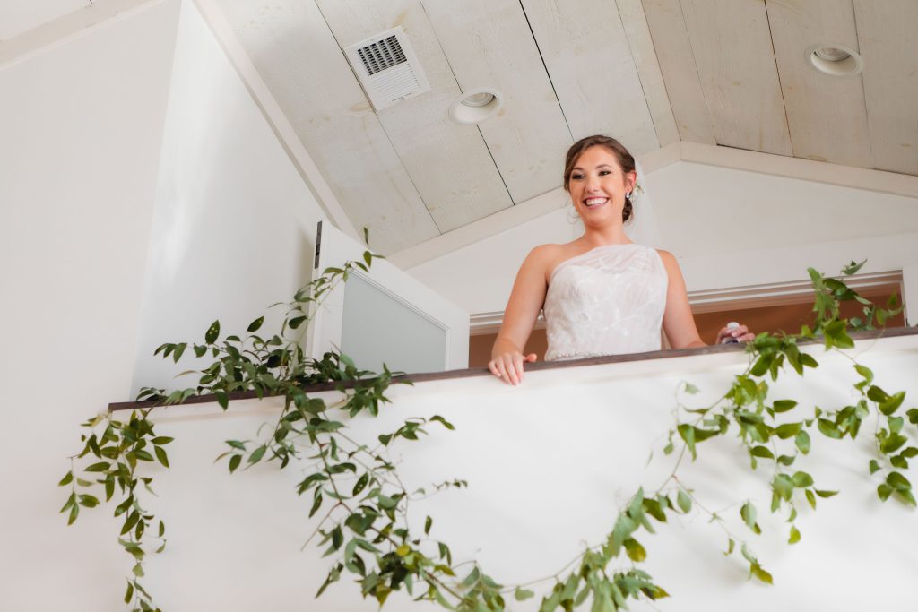 A wedding bride in a white dress standing on a balcony at Fleetwood Farm Winery.