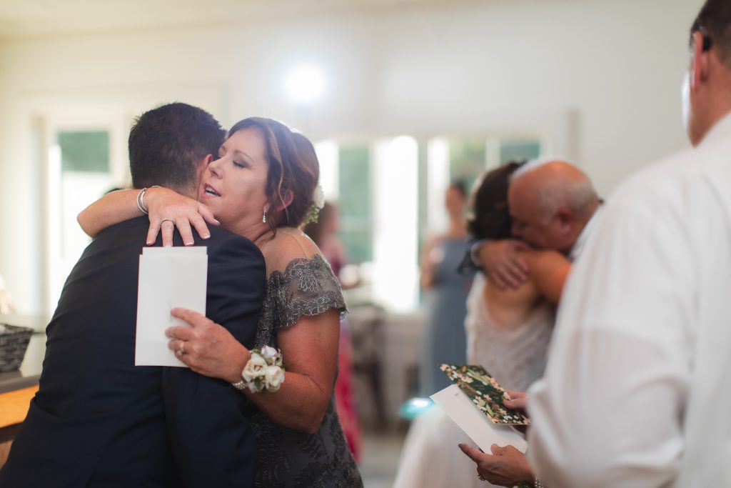 A candid moment captured during a wedding at Fleetwood Farm Winery, with a man hugging a woman.