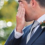 A man in a suit attending a wedding ceremony at Fleetwood Farm Winery, covers his eyes.