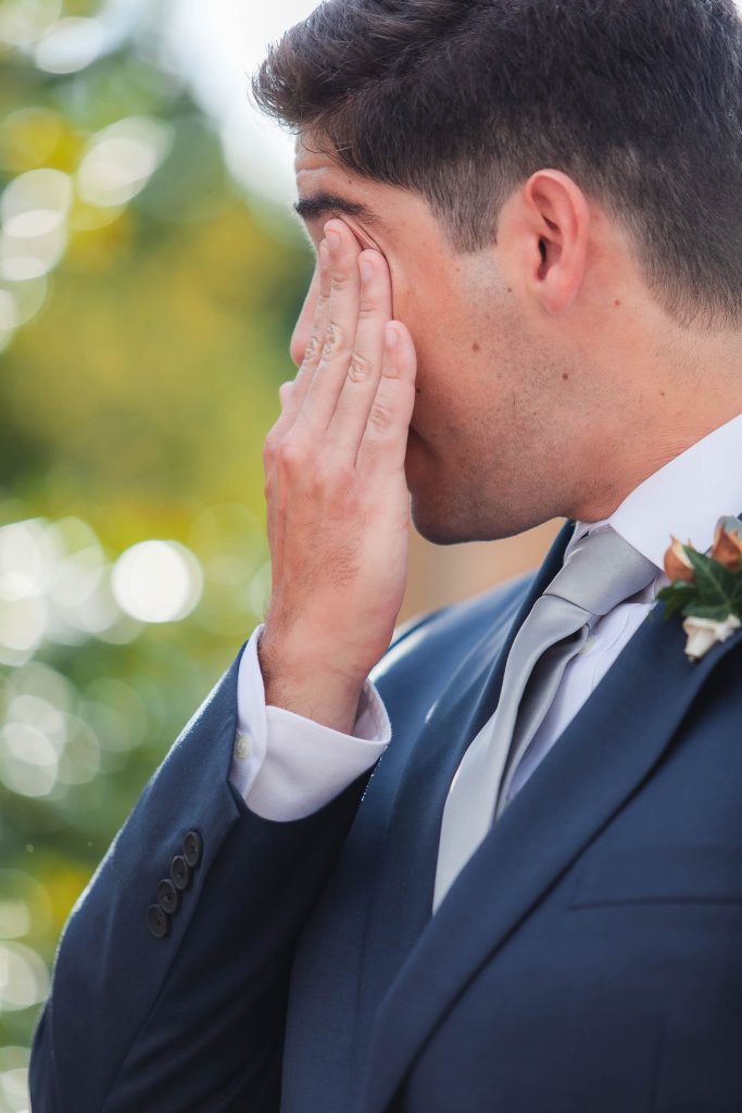 A man in a suit attending a wedding ceremony at Fleetwood Farm Winery, covers his eyes.