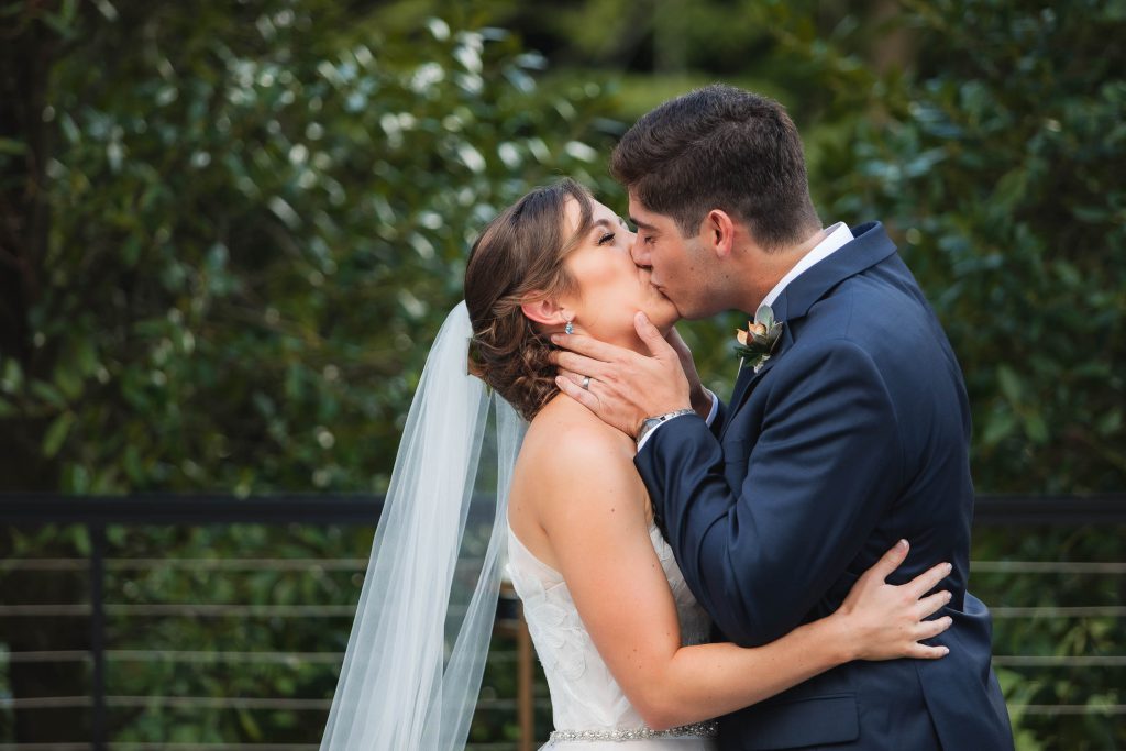 A bride and groom sharing a tender moment at their wedding ceremony in the enchanting woods of Fleetwood Farm Winery.