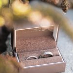 A wedding ceremony detail showcasing two glistening wedding rings enclosed in a box atop a smooth rock at Fleetwood Farm Winery.