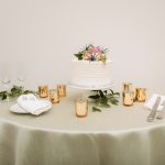 A wedding cake on a table with candles, flowers, and exquisite detail.