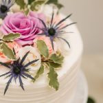 A beautiful wedding cake adorned with delicate pink and purple flowers.