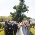 The wedding party, dressed in their finest attire, poses for a portrait amidst the scenic beauty of Fleetwood Farm Winery.