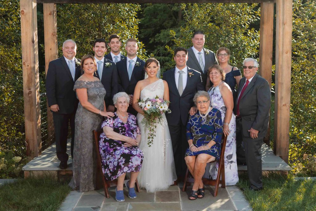A wedding party posing for a portrait in front of a pergola at Fleetwood Farm Winery.