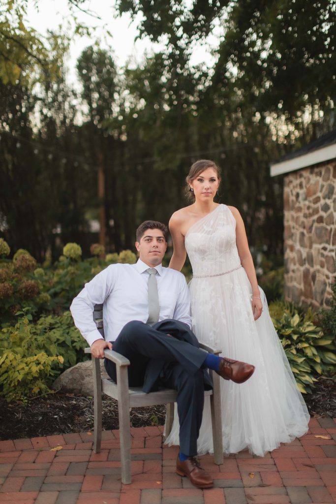 A bride and groom sitting on a chair in the garden at Fleetwood Farm Winery, captured in a beautiful portrait.