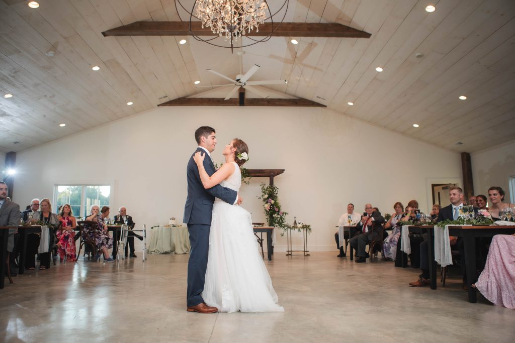 A bride and groom sharing their first dance at a wedding reception in a barn at Fleetwood Farm Winery.