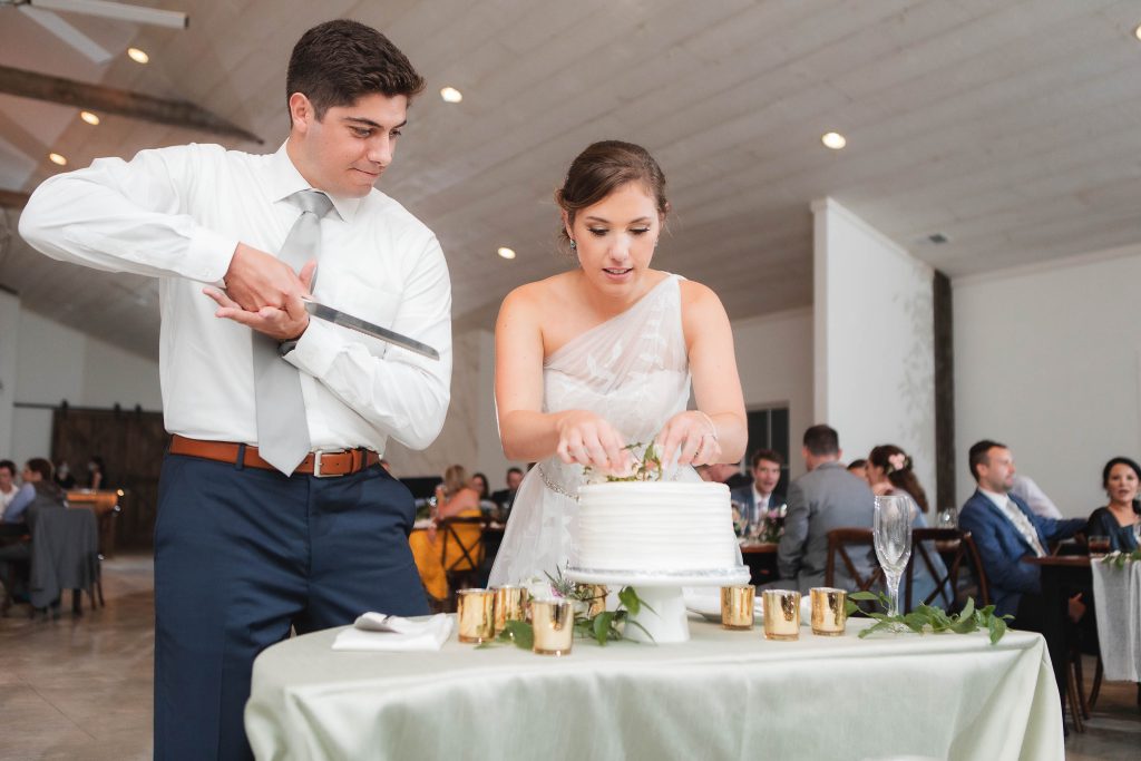 A bride and groom cutting their wedding cake at the reception held at Fleetwood Farm Winery.