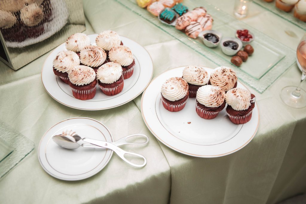 A plate of cupcakes on a table at a wedding reception, next to a glass of wine from Fleetwood Farm Winery.