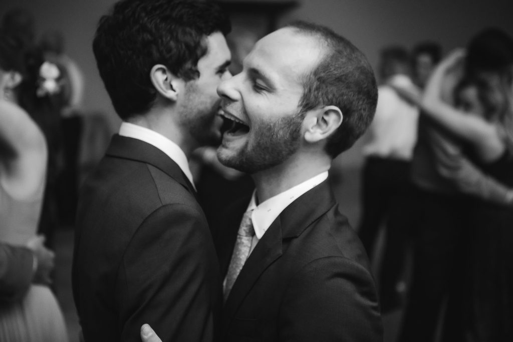 Two men sharing a kiss at a wedding reception at Fleetwood Farm Winery.