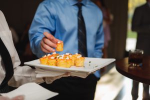 A man holding a plate of food at Main Event Catering.