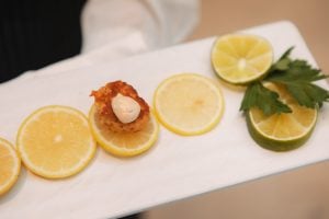 A Main Event Catering waiter is holding a tray with lemons and limes on it.