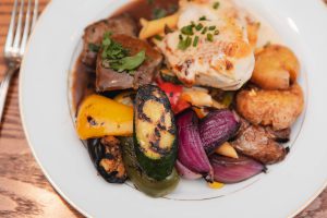 Main Event Catering showcases a delectable platter of vegetables and meat on a rustic wooden table for event vendors.